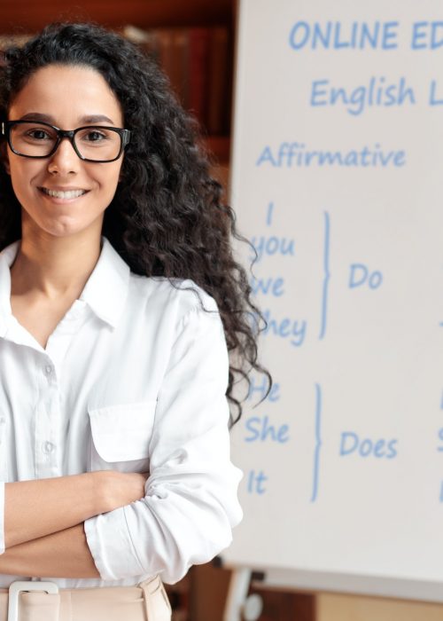 English teacher standing at board, posing at camera